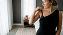 Woman adjusting bra strap under one-shoulder dress