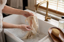 Hands rinsing a swimsuit with sunscreen stain in sink