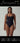 Woman modeling a black sustainable one-piece bodysuit with square neckline and high-cut legs