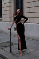 Front view of the Room 24 Verper black velvet maxi dress with one long sleeve, sweeping mesh cut-outs and a thigh-high split.