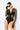 Side view of the Room 24 Maria black bodysuit showing its sheer waist panel, fitted sleeve and high-cut leg.