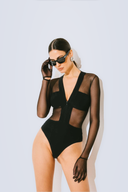 Side view of the Room 24 Maria black bodysuit showing its sheer waist panel, fitted sleeve and high-cut leg.