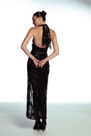 Side view of the Room 24 Iris black maxi dress showing its waist cut-out, ruched thigh slit and fitted lace silhouette.