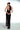 Side view of the Room 24 Iris black maxi dress showing its waist cut-out, ruched thigh slit and fitted lace silhouette.