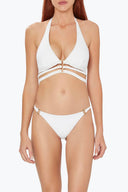 Woman wearing a white bikini with gold ring and strap cut-out details, swimwear fashion