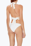 Back view of woman wearing white swimsuit with tie detail and open back