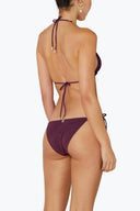 Back view of woman wearing maroon tie-back bikini with gold jewelry accents