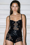 Front view of the Room 24 Lumi black sequin lace bodysuit with slim straps, structured cups and a sheer corset-style waist.