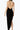 Woman in black backless halter dress with asymmetrical hem, minimalist studio background