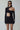 Woman wearing a black cut-out mini dress with long sleeves and asymmetrical neckline