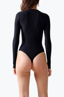Back view of the Room 24 Ruby black long-sleeve bodysuit highlighting its low back and streamlined thong silhouette.