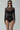 Woman wearing black mesh long sleeve bodysuit with sheer cut-out panels, fashion jewelry