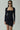 Front view of the Room 24 Jessica black mini dress with a square neckline, long sleeves and asymmetric draped hem.