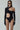 Woman wearing black sustainable bodysuit with long sleeves, cut-outs, and sunglasses