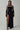 Woman in black velvet evening gown with mesh neckline, high slit, gloves and hoop earrings