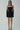 Front view of the Room 24 Sola black mini dress with a sheer illusion neckline, long glove sleeves and flared A-line skirt.