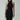 Woman in black halter neck dress with sunglasses, cream handbag, and silver bangles