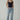 Woman in black bodysuit, distressed jeans, and heels, modeling casual fashion
