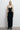 Front view of the Room 24 Kaya black maxi dress with a deep V neckline, geometric waist cut-outs and fitted silhouette.