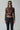 Woman in bronze long sleeve top and black leather pants with sunglasses and silver jewelry