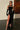 Front view of the Room 24 Samantha black velvet maxi dress with a sheer illusion neckline, fitted bodice and thigh-high split.