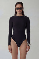 Front view of the Room 24 Ruby black long-sleeve bodysuit with a round neckline, high-cut legs and sculpted close fit.