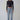 Woman in black long sleeve crop top, light blue high-waisted jeans, and black heels