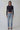 Woman in black long sleeve crop top, light blue high-waisted jeans, and black heels