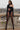 Woman in a black asymmetric cut-out bodysuit with sheer tights posing outdoors