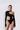 Front view of the Room 24 Bridget black asymmetric bodysuit with a high neckline, curved waist cut-out and glove sleeves.