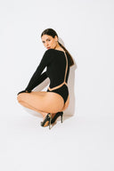 Side view of the Room 24 Regina black bodysuit showing its mesh sleeve insert, geometric waist detailing and sculpted close fit.