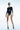 Front view of the Room 24 Dorina black bodysuit with a curved under-bust cut-out, illusion-mesh sleeves and waist belt.