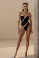 Front view of the Room 24 Eva black strapless bodysuit with sculpted opaque panels and asymmetric sheer mesh cut-outs.