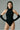Woman modeling sleek black sleeveless bodysuit with high neckline and matching long gloves
