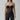 Woman wearing a black strapless mesh corset top and high-waisted faux leather pants