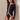 Side view of the Room 24 Regina black bodysuit showing its mesh sleeve insert, geometric waist detailing and sculpted close fit.