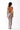 Woman in sheer mesh maxi dress with asymmetric open back and cut-out detail, studio setting