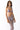 Woman in lavender metallic bikini with sheer mesh cut-out dress, sunglasses, white background