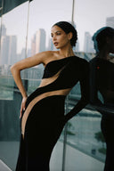 Front view of the Room 24 Verper black velvet maxi dress with one long sleeve, sweeping mesh cut-outs and a thigh-high split.